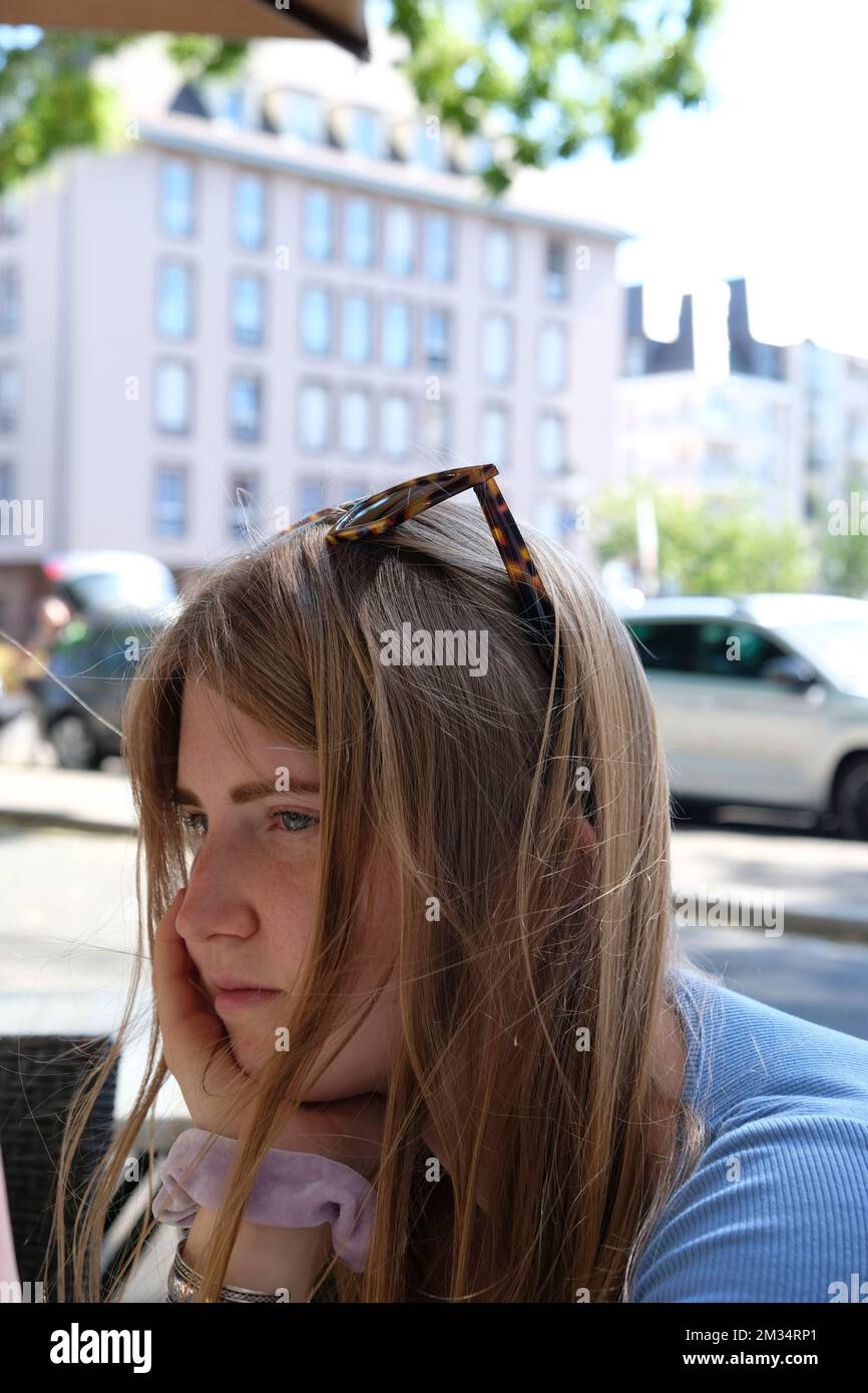 La giovane donna si annoia in un caffè di strada Foto Stock