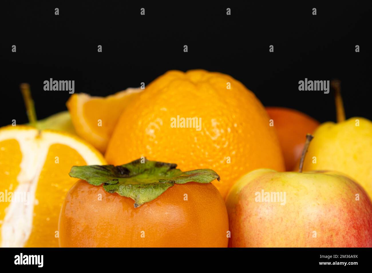 Frutti di colore arancio e giallo - mele, persimmoni e arance su sfondo nero Foto Stock