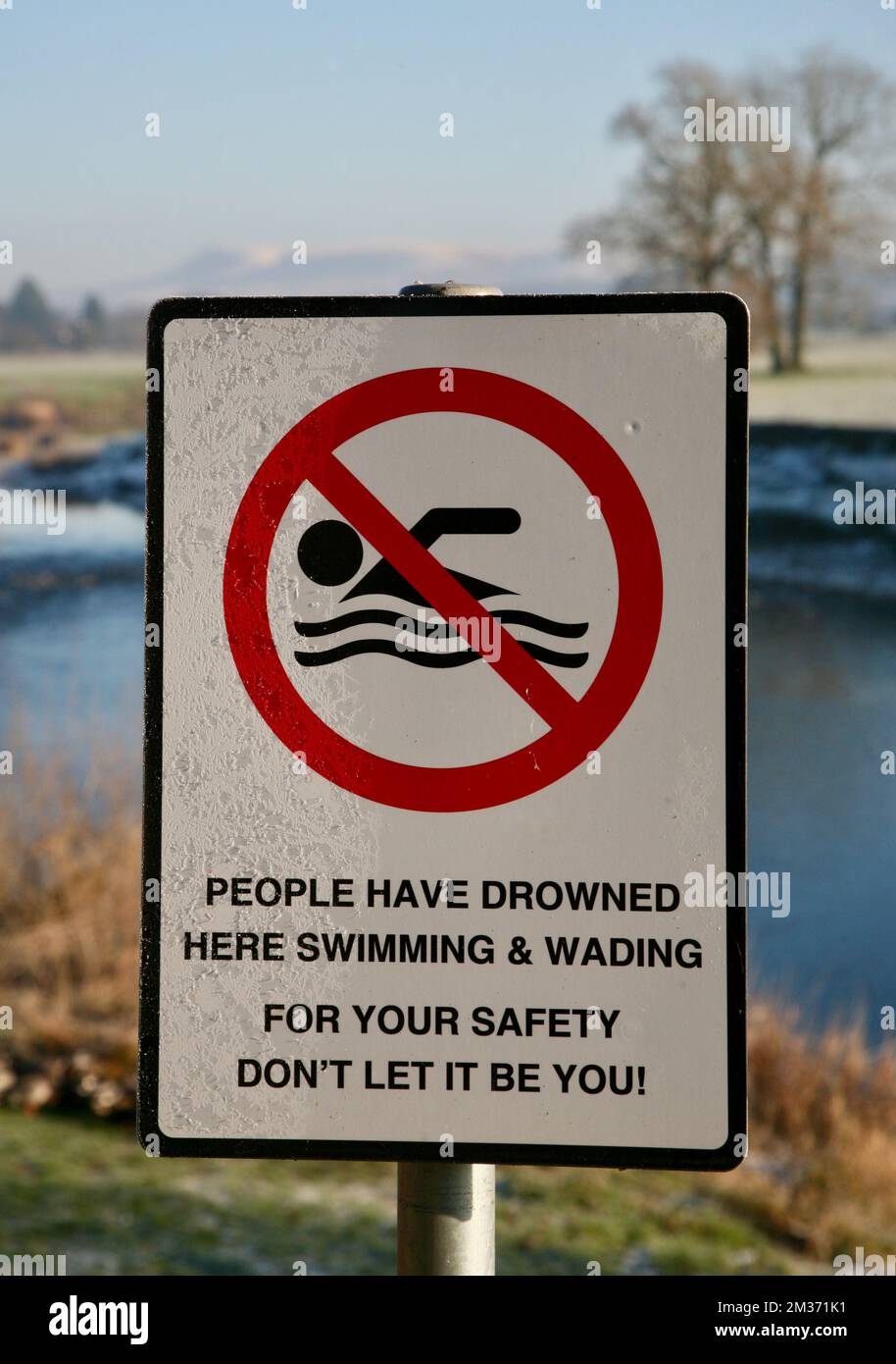 Un cartello sulla riva del fiume che identifica i pericoli del nuoto nel fiume Ribble a Ribchester, Lancashire, Regno Unito, Europa Foto Stock