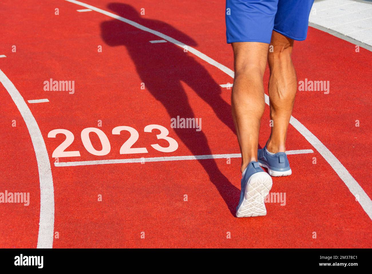 Runner attraversa la linea a partire dal 2023 su un tapis roulant rosso con i numeri 2023. Concetto di ingresso per il nuovo anno, passo Foto Stock