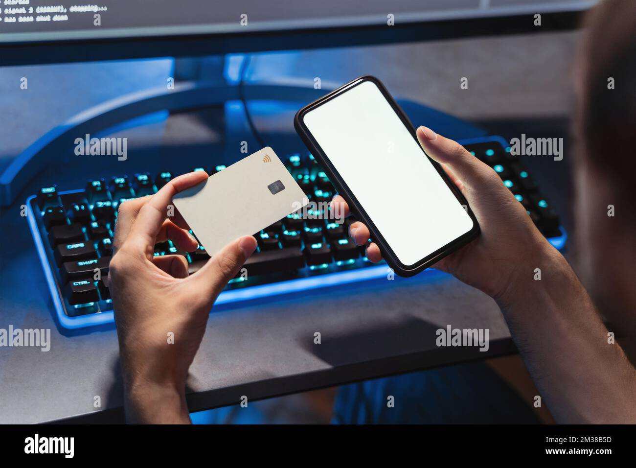 Primo piano delle mani maschili che tengono la carta di credito e lo smartphone con schermata bianca mockup Copy Space per i tuoi contenuti pubblicitari. Giocatore che acquista l'accesso a un nuovo livello utilizzando il telefono e la carta bancaria. Foto Stock