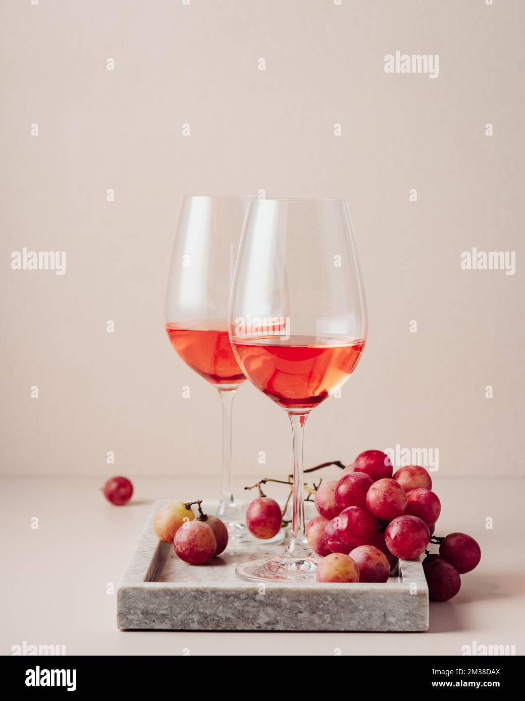 Due bicchieri di vino rosato e un mazzo di uve rosse. Foto Stock
