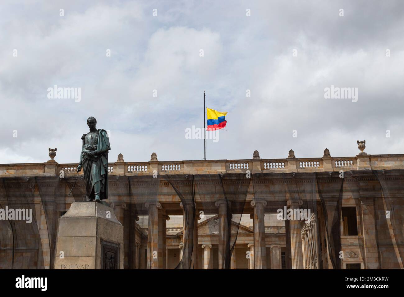 BOGOTÀ, COLOMBIA - Chiudiare la scultura di Simon Bolivar con la bandiera colombiana di midpole che sventola e la casa presidenziale sullo sfondo Foto Stock