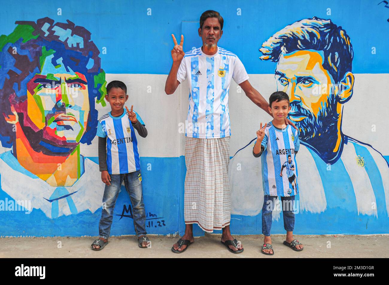 14 dicembre 2022 a Sylhet, Bangladesh: I fan argentini festeggiano, si pone davanti a un murale del suo eroe, Lionel messi, vince la Croazia nella partita semifinale di ieri sera e si qualificano per la finale di Coppa del mondo 2022. Bangladesh, un paese che non è mai stato qualificato per una Coppa del mondo di calcio; ma ha un grande amore per il calcio e ha tifosi seguaci enormi sia per l'Argentina che per il Brasile. Il 14 dicembre 2022 a Sylhet, Bangladesh (Foto di MD Rafayat Haque Khan/ Eyepix Group) Foto Stock