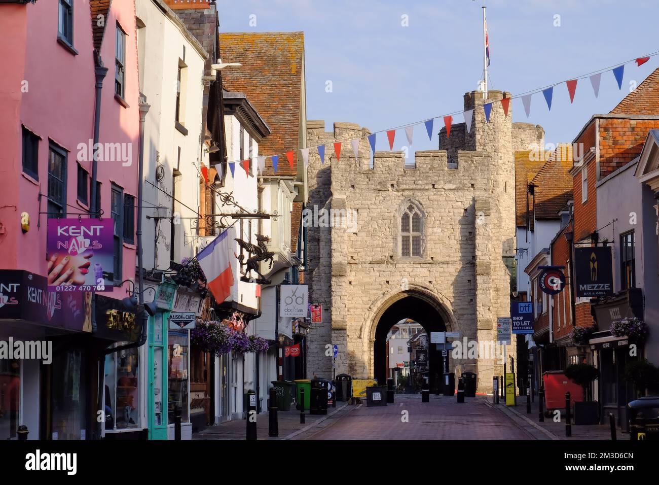 Westgate Towers, il castello medievale subito dopo l'alba e i negozi di St Peter's Street (High Street), Canterbury, Kent, Inghilterra Foto Stock