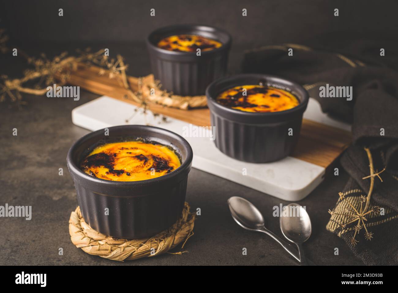 Crème brulee. Ciotole con dessert alla crema alla vaniglia francese con  zucchero caramellato sulla parte superiore, cucchiai, tavolo rustico scuro  Foto stock - Alamy