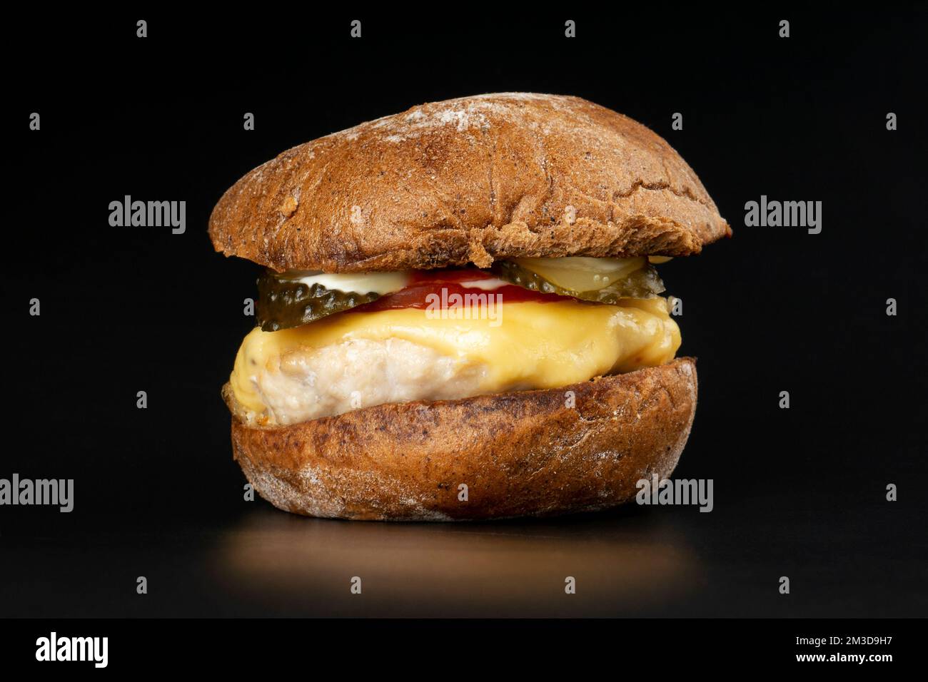 hamburger succoso con un primo piano marrone, cheeseburger con cotoletta di pollo, formaggio e verdure su sfondo scuro. Foto Stock