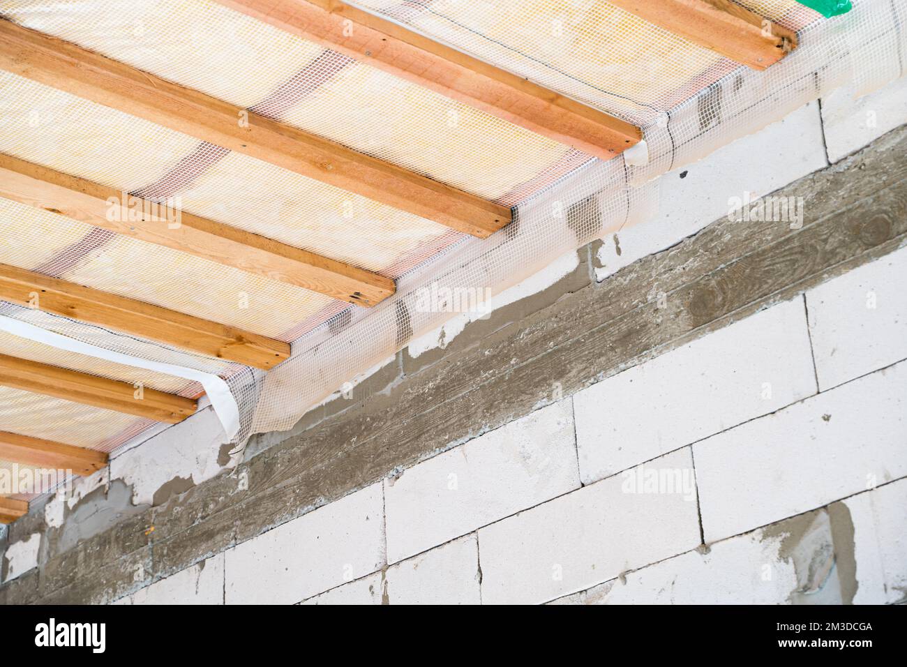 Soffitto isolato di una casa privata con una cassa di legno. Il tetto è isolato con lana di vetro e rivestito con una barriera al vapore, vista dal basso Foto Stock