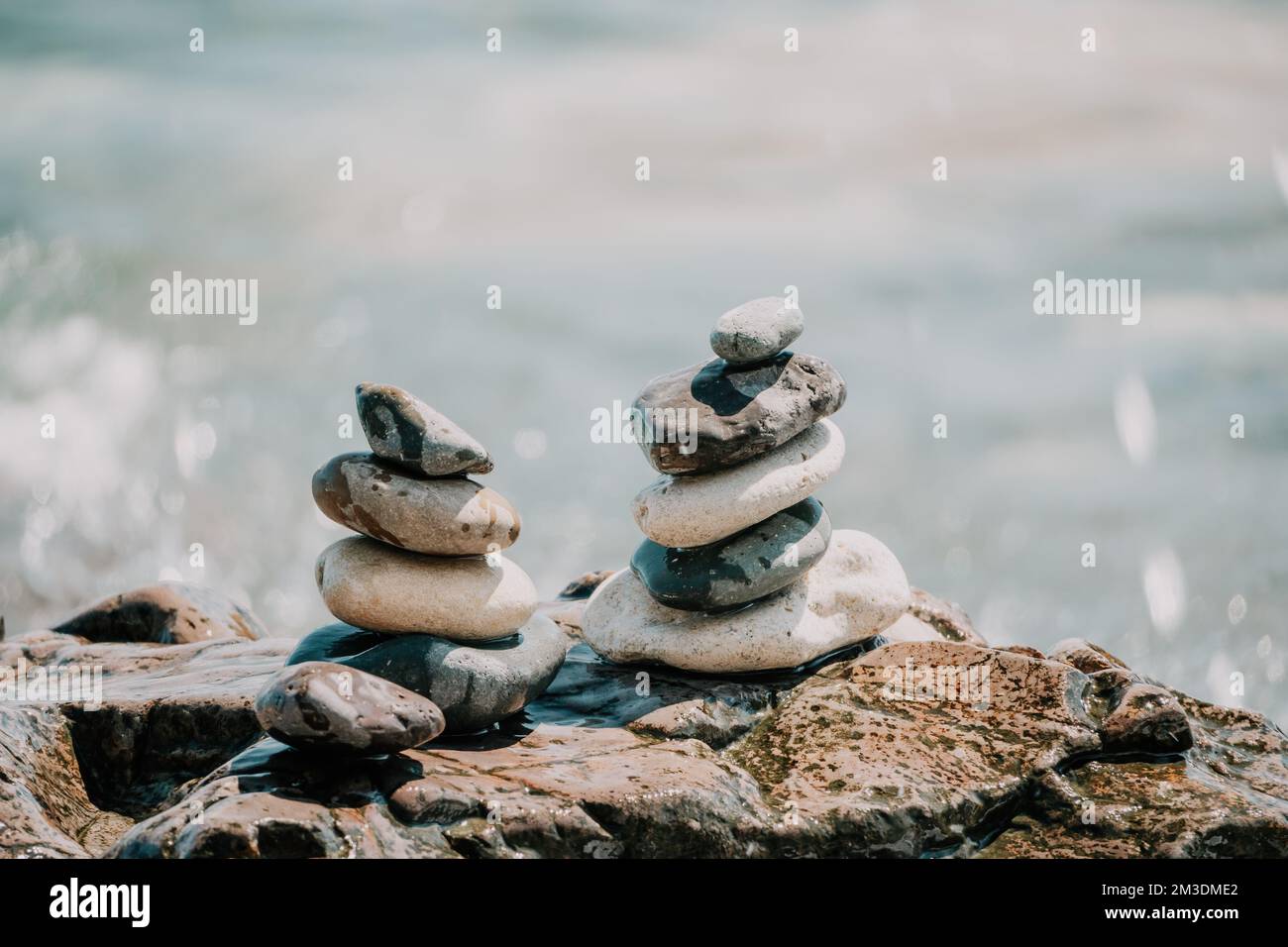 Piramide di roccia bilanciata sulla spiaggia di ciottoli, giorno di sole e cielo limpido al tramonto. Bokeh Golden Sea sullo sfondo. Fuoco selettivo, pietre zen sulla spiaggia di mare Foto Stock