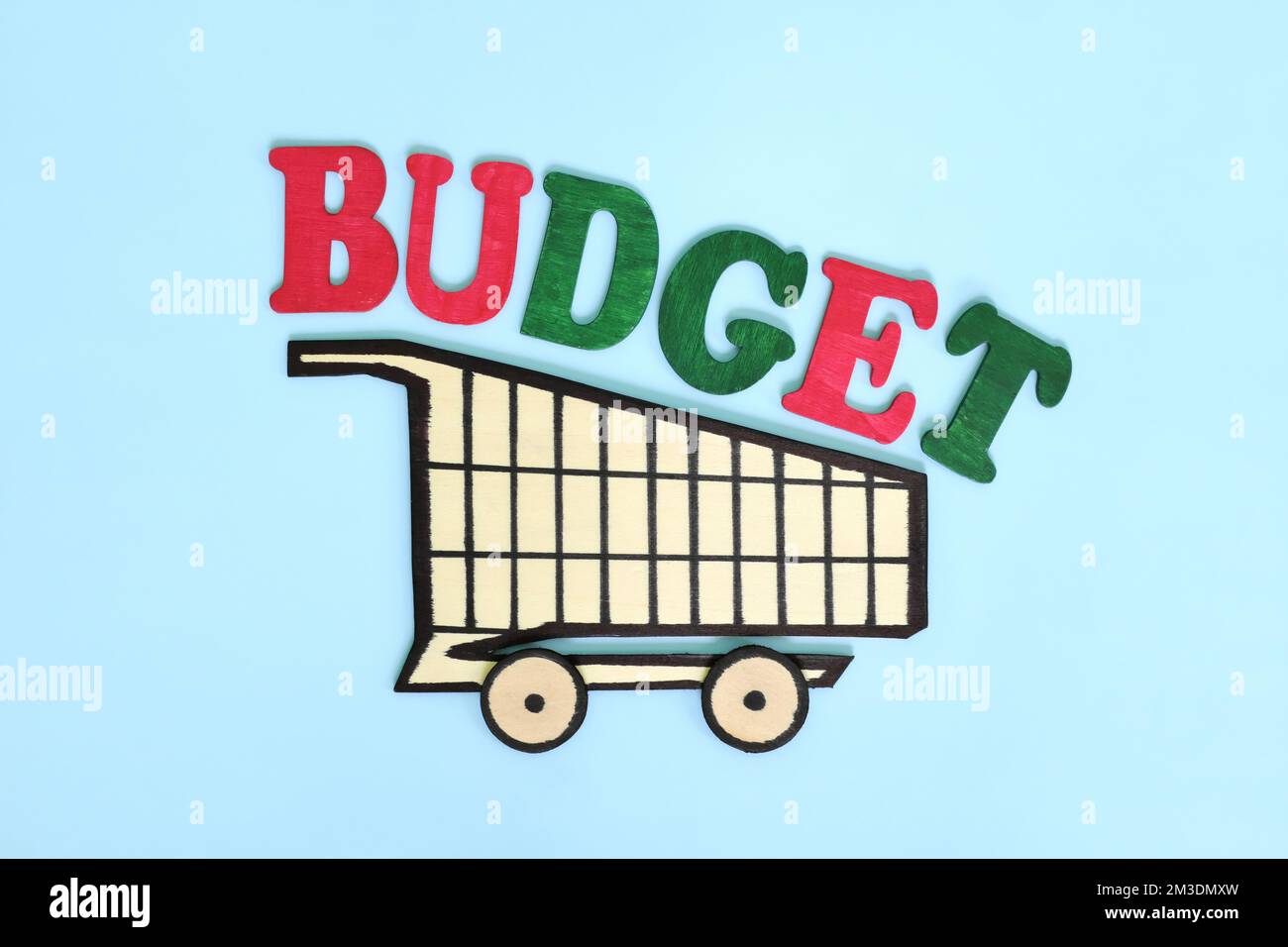 Concetto di budget per lo shopping. Carrello in legno con parola su sfondo blu. Foto Stock