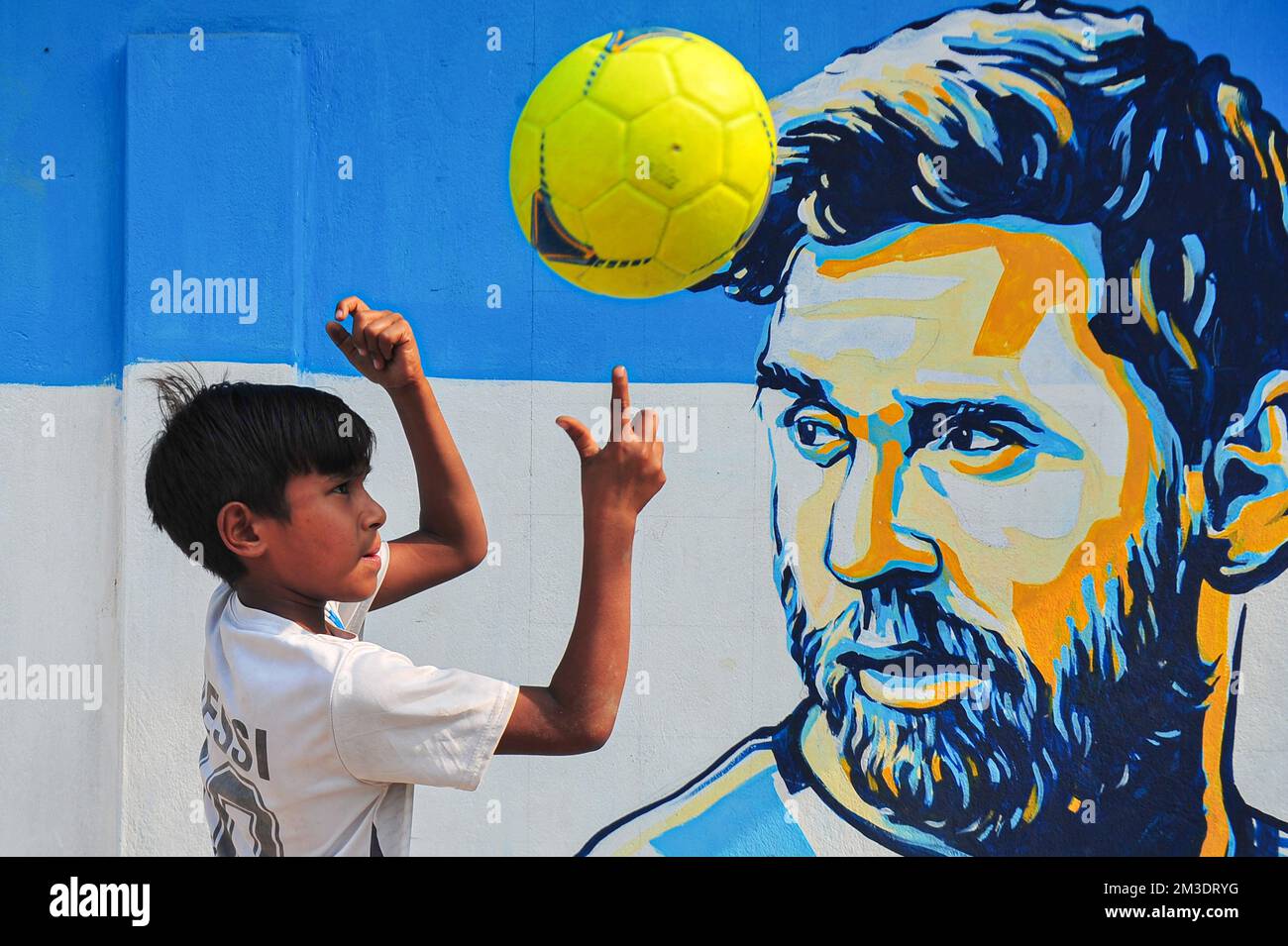 Non esclusiva: 14 dicembre 2022 a Sylhet, Bangladesh: Giovani tifosi argentini che festeggiano, posa davanti a un murale del suo eroe, Lionel messi, vince Cro Foto Stock