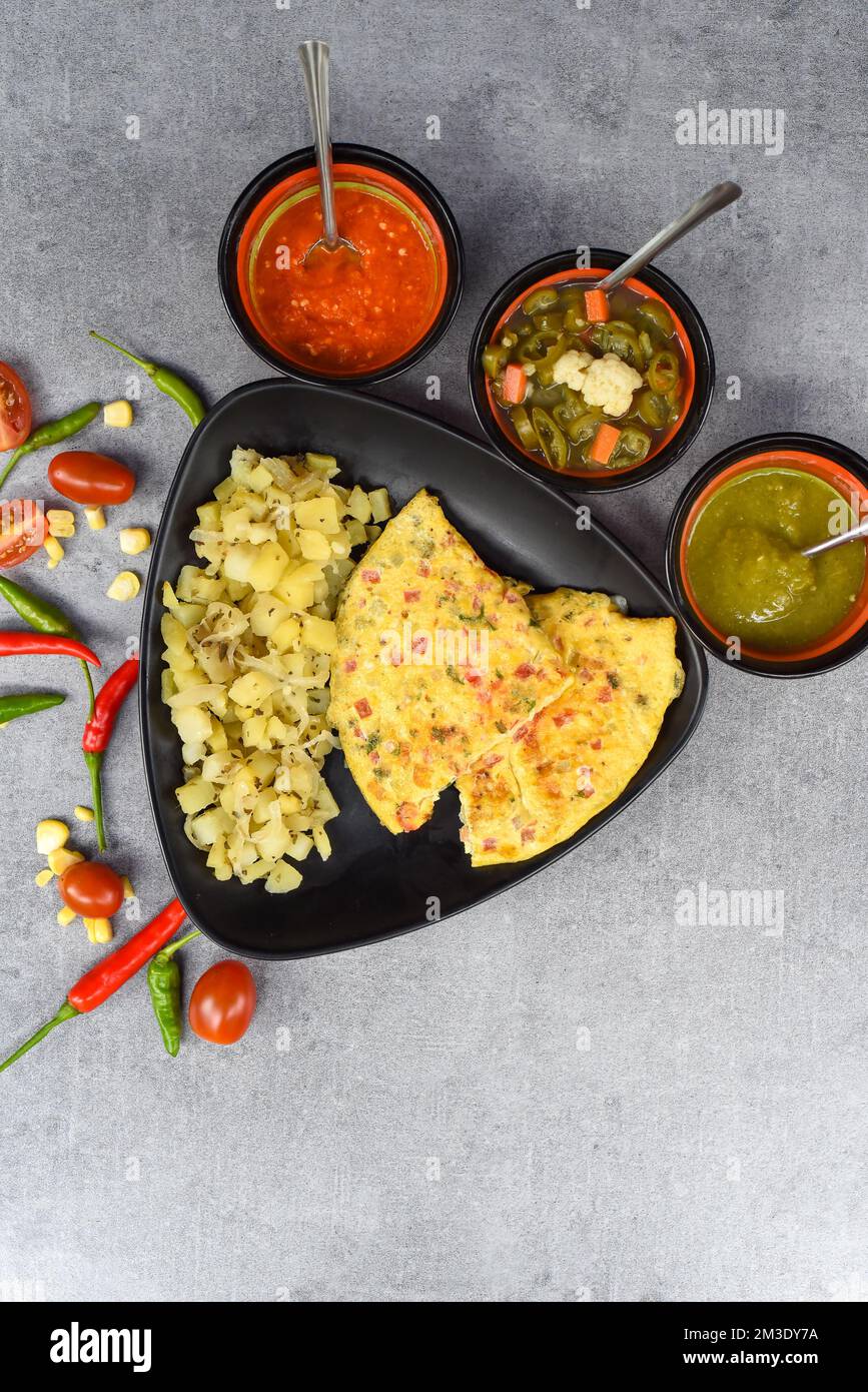 Frittata messicana con patate su piatto nero con cibo latino-americano su sfondo grigio Foto Stock