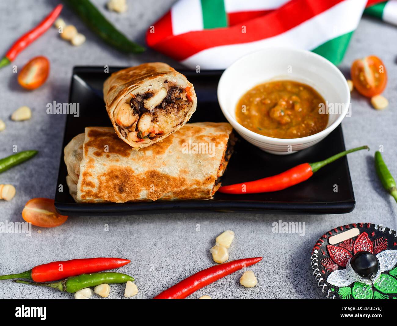 Burrito messicano con pollo, riso, fagioli e formaggio servito con salsa barracha Foto Stock