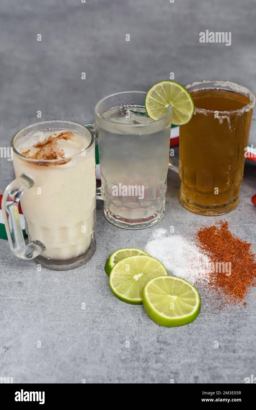 Bevande messicane acqua di Horchata, succo di lime e birra su un tavolo grigio con pepe di sale e lime Foto Stock