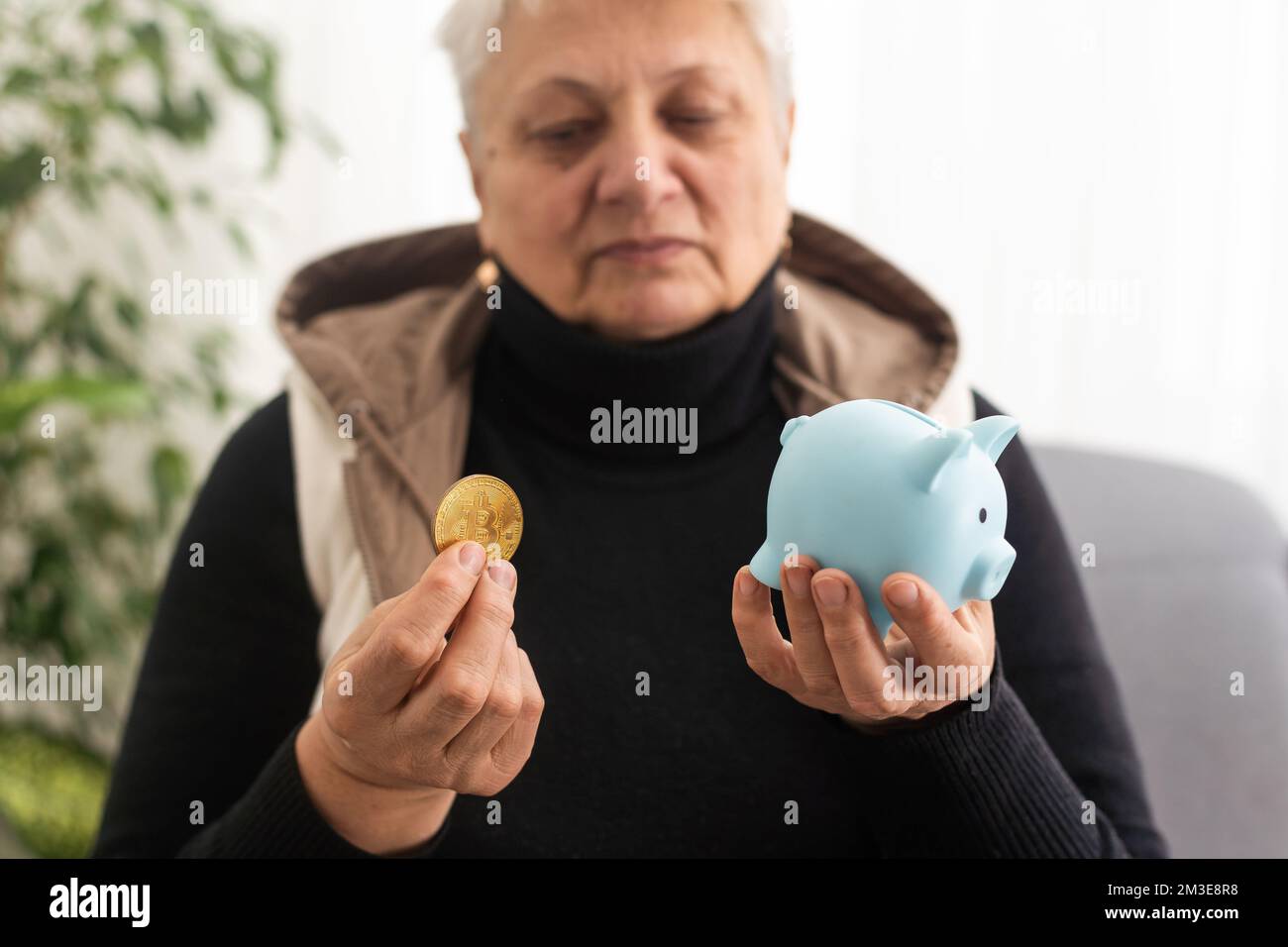 Primo piano di una donna anziana in possesso di una scatola di denaro di maiale. Mani di donna anziana che tengono un piggybank. Concetto di risparmio di denaro per la vecchiaia. Foto Stock