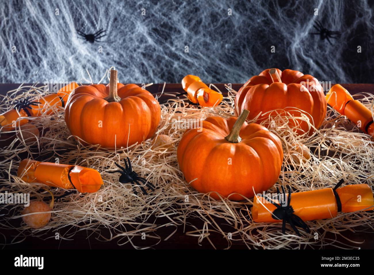 Zucche, caramelle, ragni e paglia decorato ragnatela su sfondo nero, concetto di Halloween festa Foto Stock