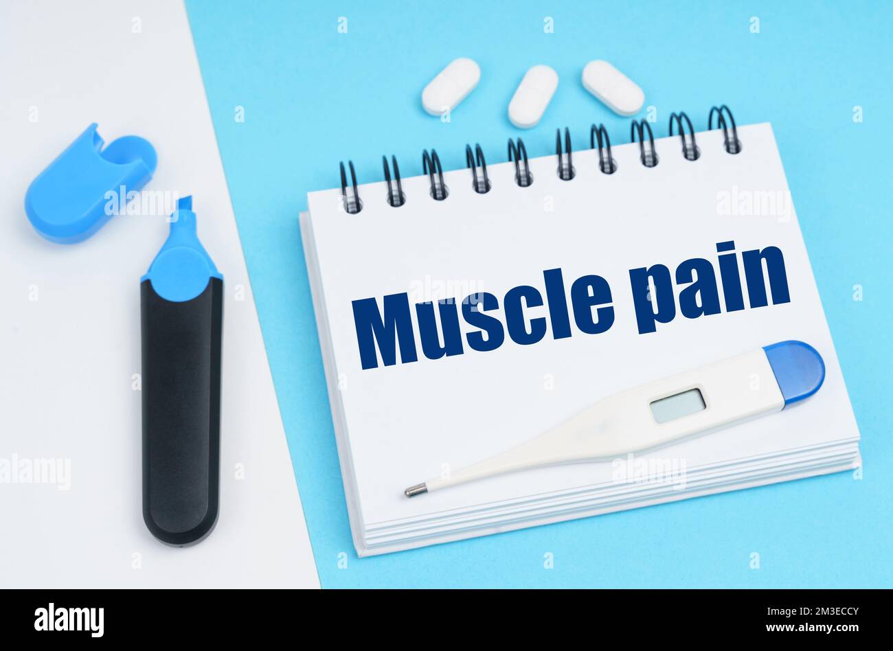 Concetto di diagnosi medica. Su una superficie bianco-blu ci sono pillole, un termometro, un marcatore e un notebook con l'iscrizione - dolore muscolare Foto Stock