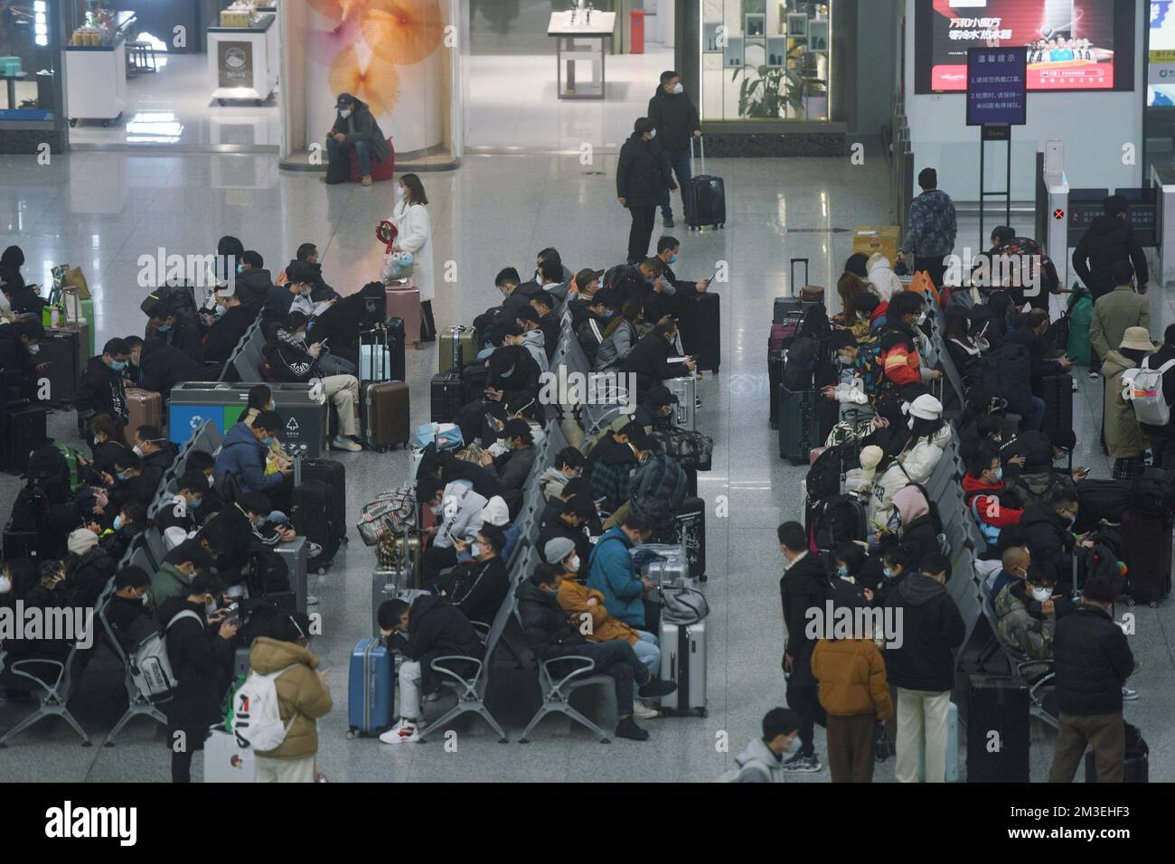 HANGZHOU, CINA - 15 DICEMBRE 2022 - Un gran numero di passeggeri che indossano maschere aspettano nella sala d'attesa della stazione ferroviaria di Hangzhou Est Foto Stock