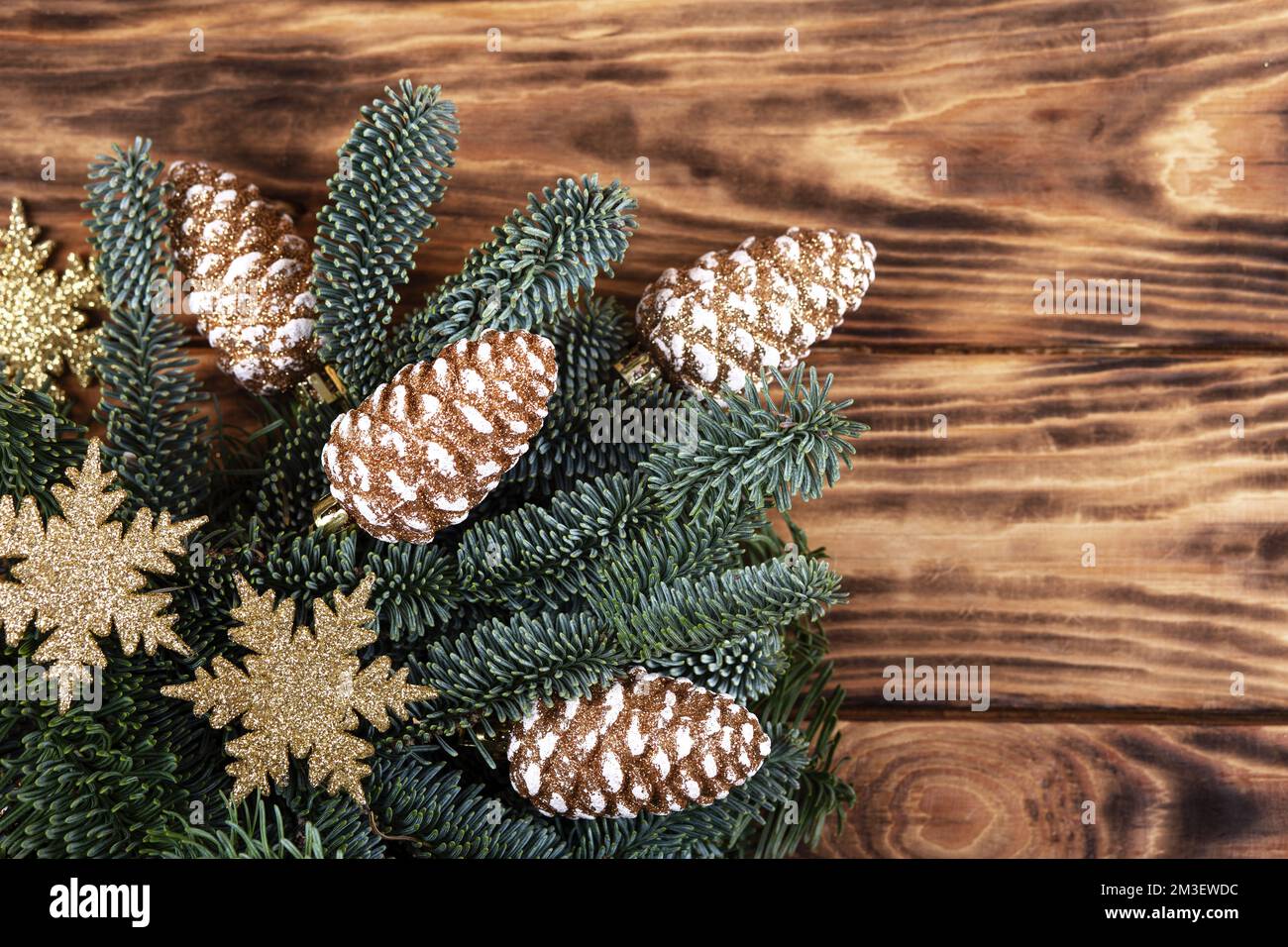 Rami verdi di un albero di Natale con decorazioni in forma di coni dorati su uno sfondo di legno con un posto per il testo. Vista dall'alto Foto Stock
