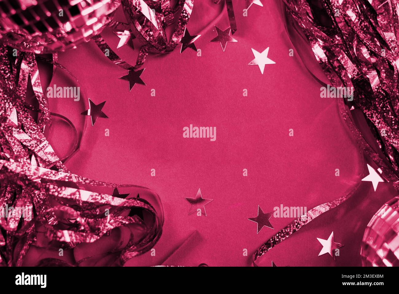 Confetti, e palle da discoteca su sfondo di Capodanno o Natale con decorazioni natalizie su un colore Viva Magenta dell'anno. Con Copia spazio per i messaggi di saluto Foto Stock