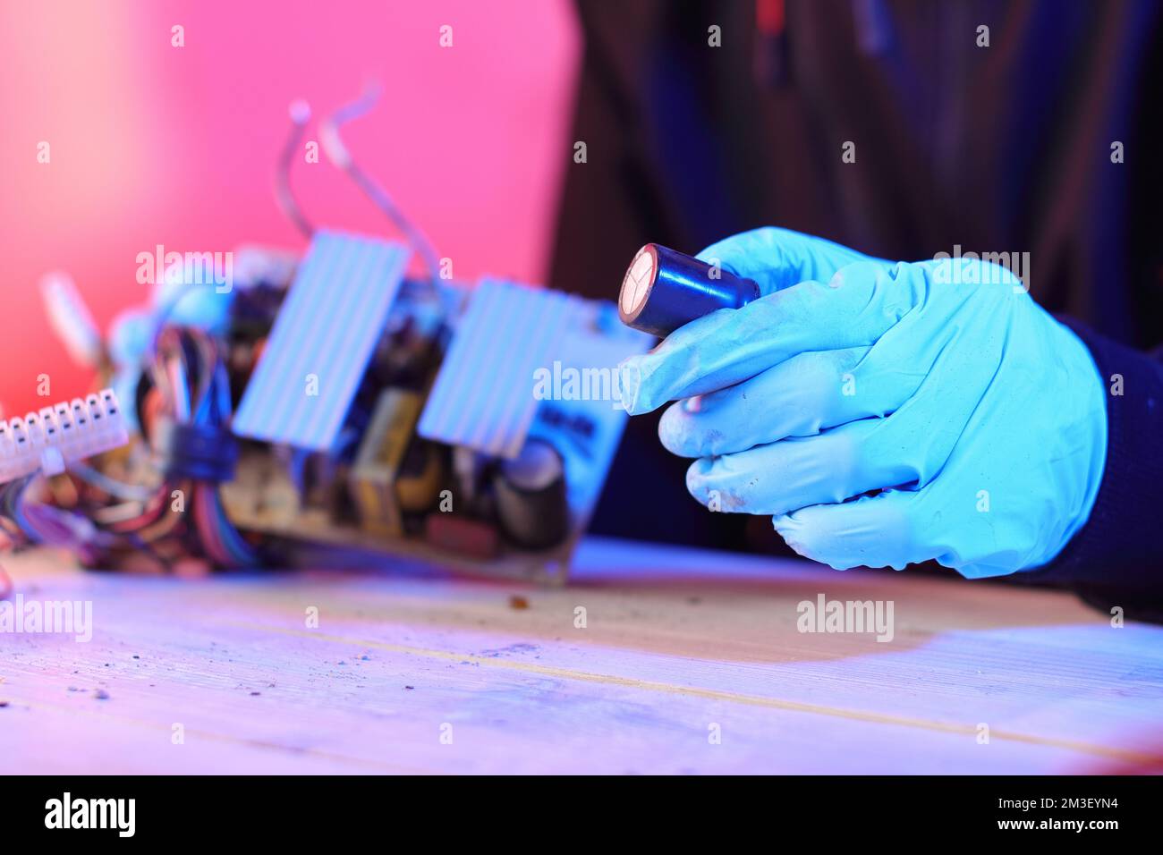 condensatore elettrico dall'alimentazione del calcolatore in mano su sfondo colorato Foto Stock