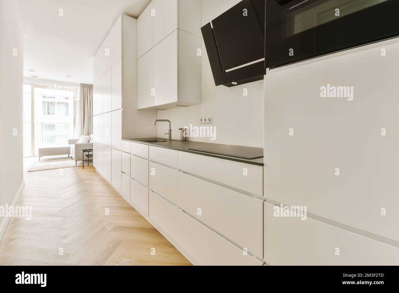 una cucina con armadi bianchi e elettrodomestici neri sui ripiani di questa camera è molto pulita, ma non è così Foto Stock