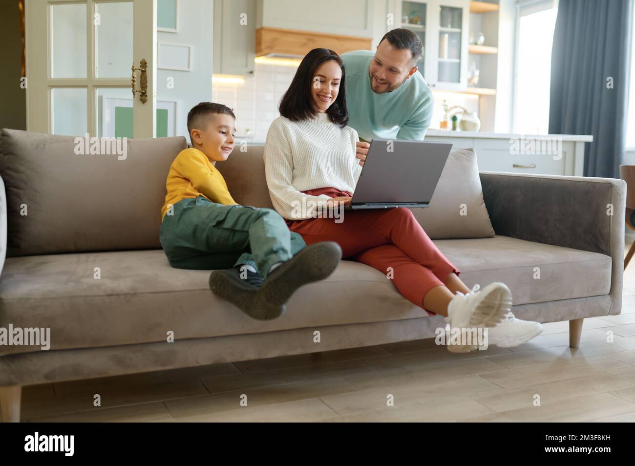 Famiglia felice a casa con madre che lavora su un notebook Foto Stock
