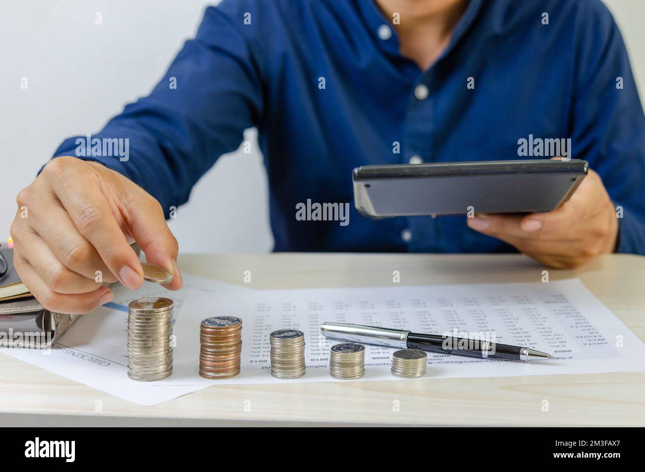 Businessman che tiene la pila della moneta sulla scrivania.Business investimento finanza soldi di risparmio bancario e gestione contabile di marketing concetto. Foto Stock