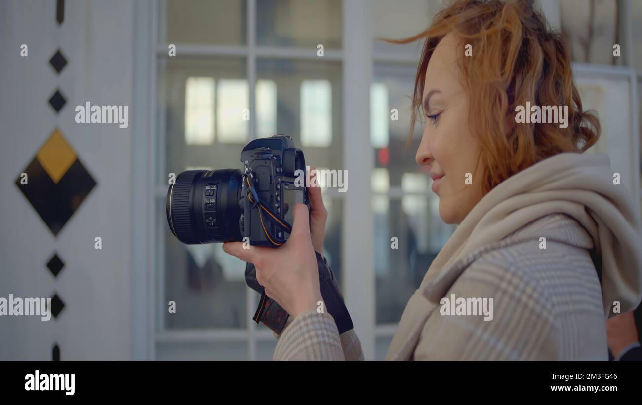 Primo piano del fotografo che tiene una fotocamera professionale. Azione. La fotocamera è nelle mani di un giovane fotografo professionista. Donna scatta foto con la fotocamera. Foto Stock