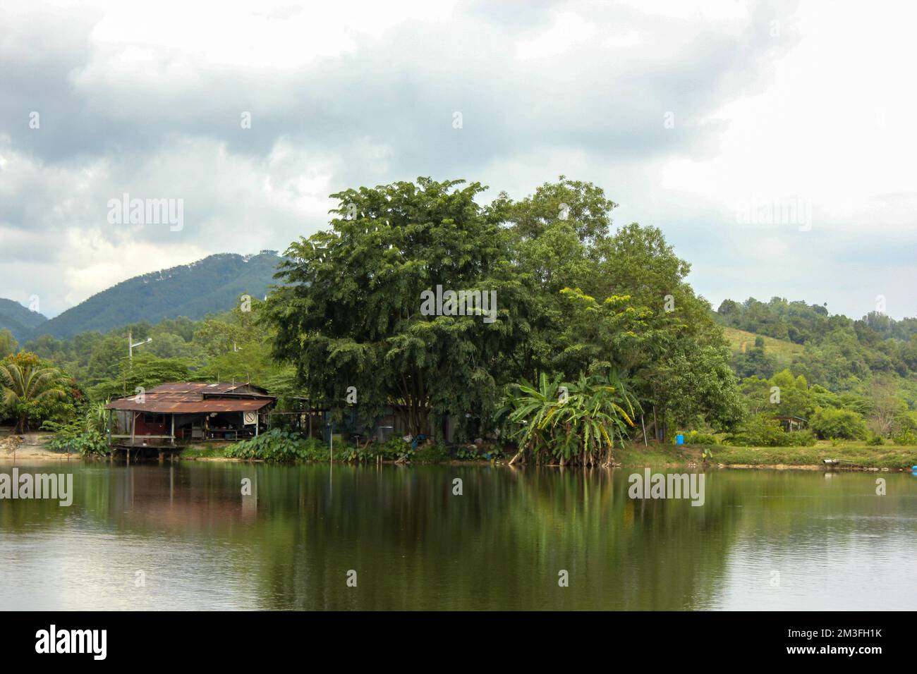 Vista panoramica di un villaggio lungo il fiume con lussureggianti dintorni verdi nella periferia della città di Ipoh in Malesia. Foto Stock