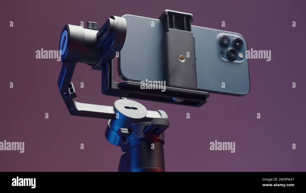 Stabilizzatore per smartphone con tre fotocamere isolate su una parete rosa. Azione. Nuova soluzione professionale per le riprese e un telefono Foto Stock