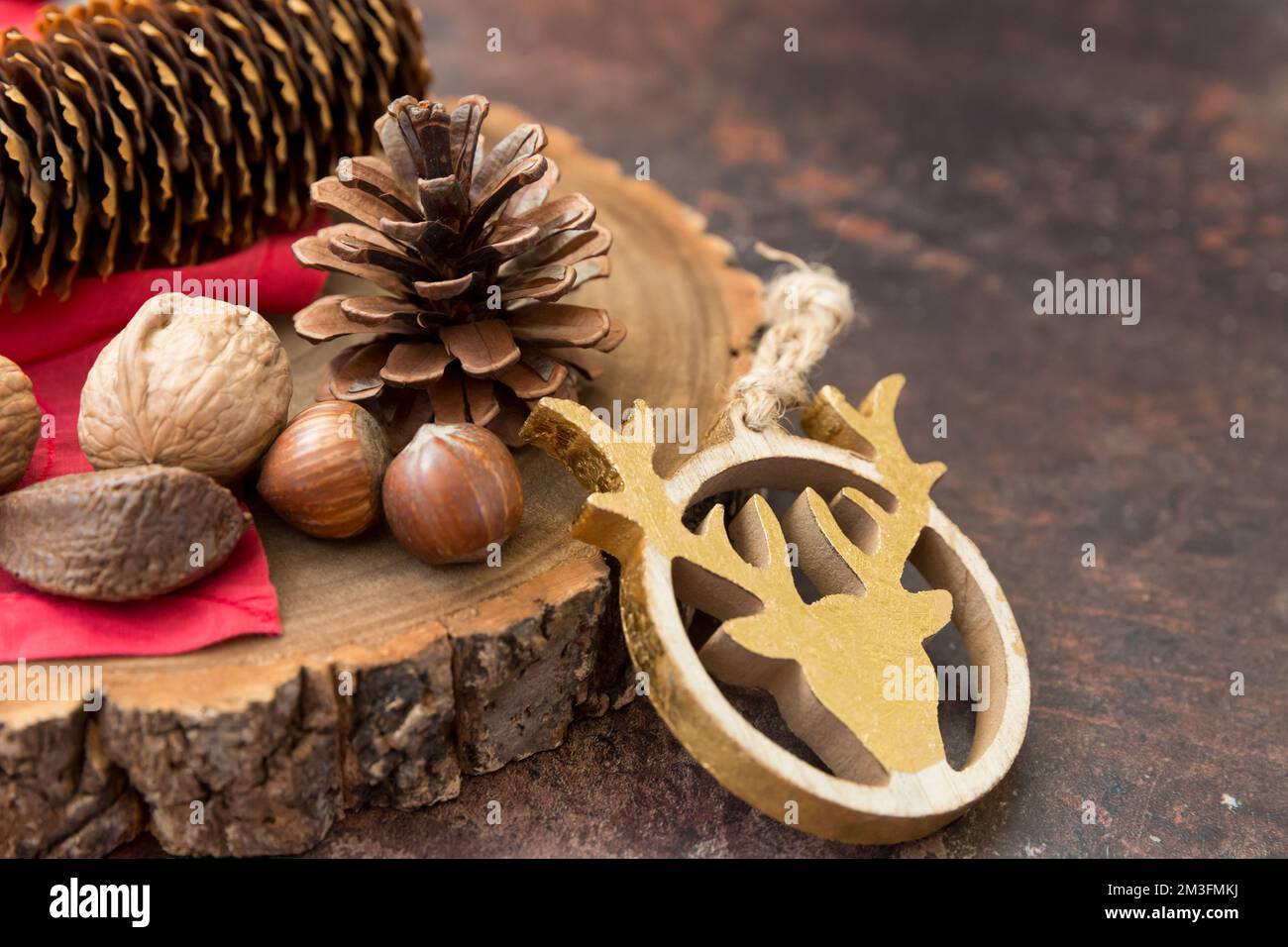 Natura morta festosa con spazio per copia contenente noci e pinici su un blocco di legno con tovagliolo rosso e sfondo scuro. Foto Stock