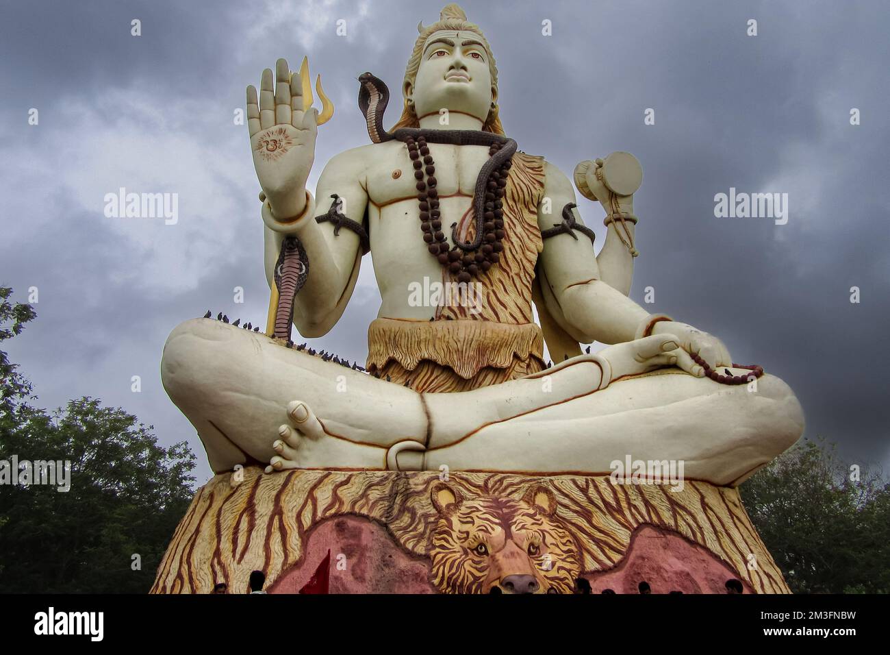 Un angolo basso di una statua bianca di Lord Shiva sotto un cielo nuvoloso in Nageshwar Rd, Dwarka, Gujarat, India Foto Stock