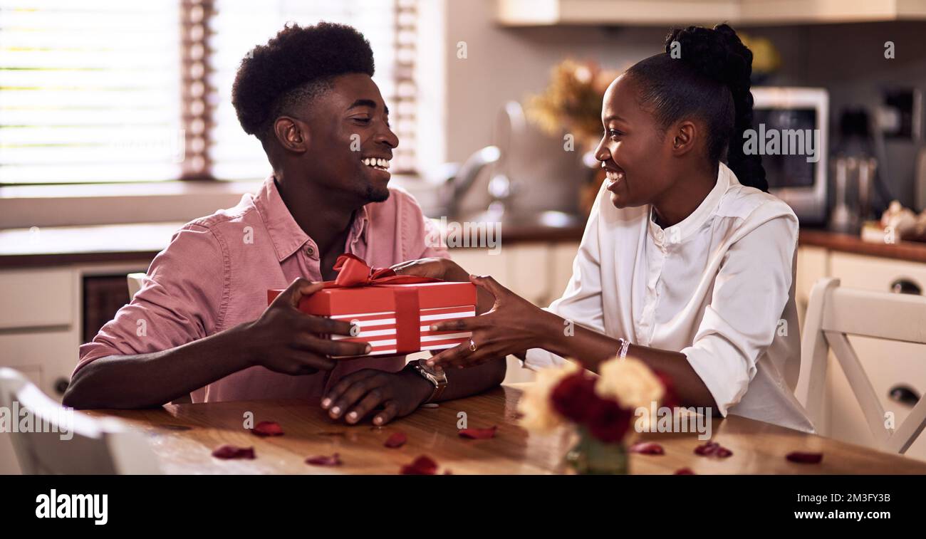 Vuoi indovinare cosa c'è qui. Un giovane affettuoso che dona alla moglie un regalo avvolto il giorno di San Valentino a casa. Foto Stock