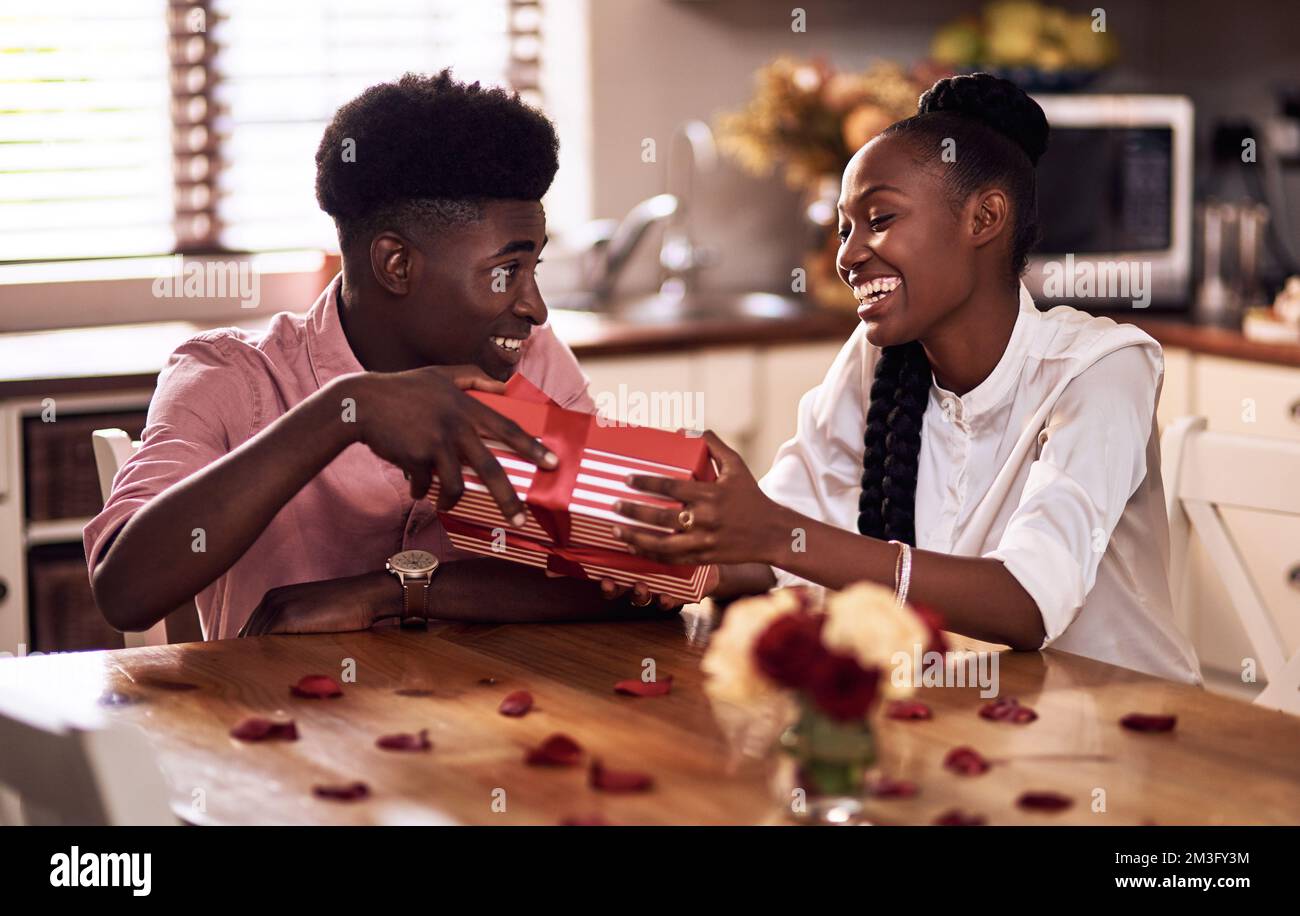 Im sicuro che youll amore questo. Un giovane affettuoso che dona alla moglie un regalo avvolto il giorno di San Valentino a casa. Foto Stock