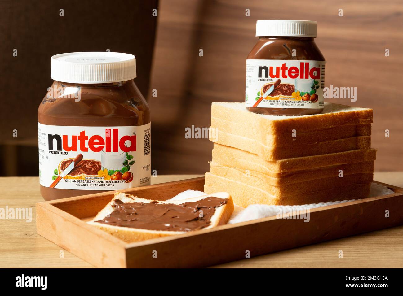 Nutella con bottiglie grandi e piccole e un po' di pane bianco ordinato sul tavolo da pranzo Foto Stock