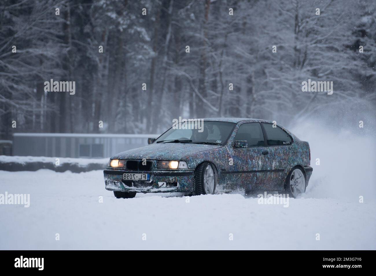12-12-2022 riga, Lettonia un'auto che guida attraverso una foresta coperta di neve in inverno con alberi sullo sfondo e una spolverata di neve sul groun Foto Stock