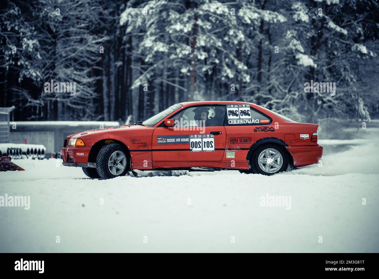 12-12-2022 riga, Lettonia una macchina rossa parcheggiata nella neve vicino a una foresta con un cartello sul lato che dice motoslitta. . Foto Stock