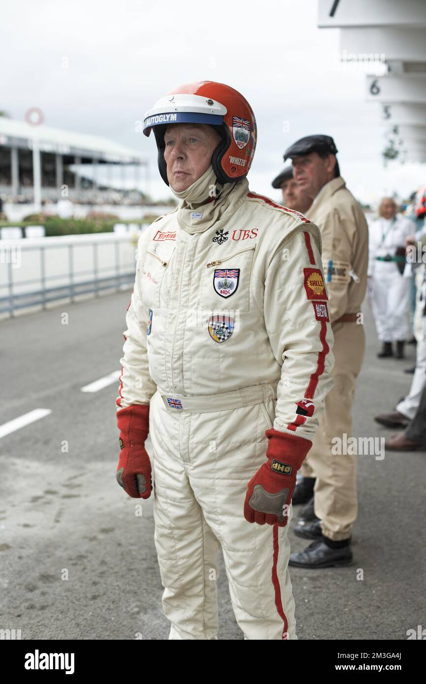 West Sussex, Inghilterra : pilota di auto da corsa che guarda la gara nel paddock al Goodwood Revival . Foto Stock