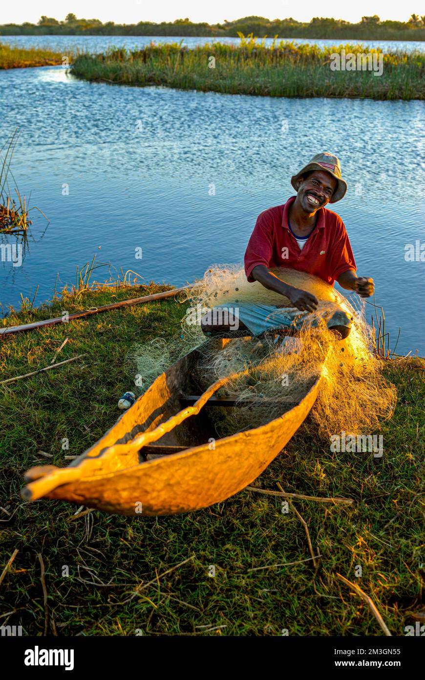 Fisherman ripara la sua rete al tramonto, Canal des Pangalanes, Mankara, Madagascar Foto Stock