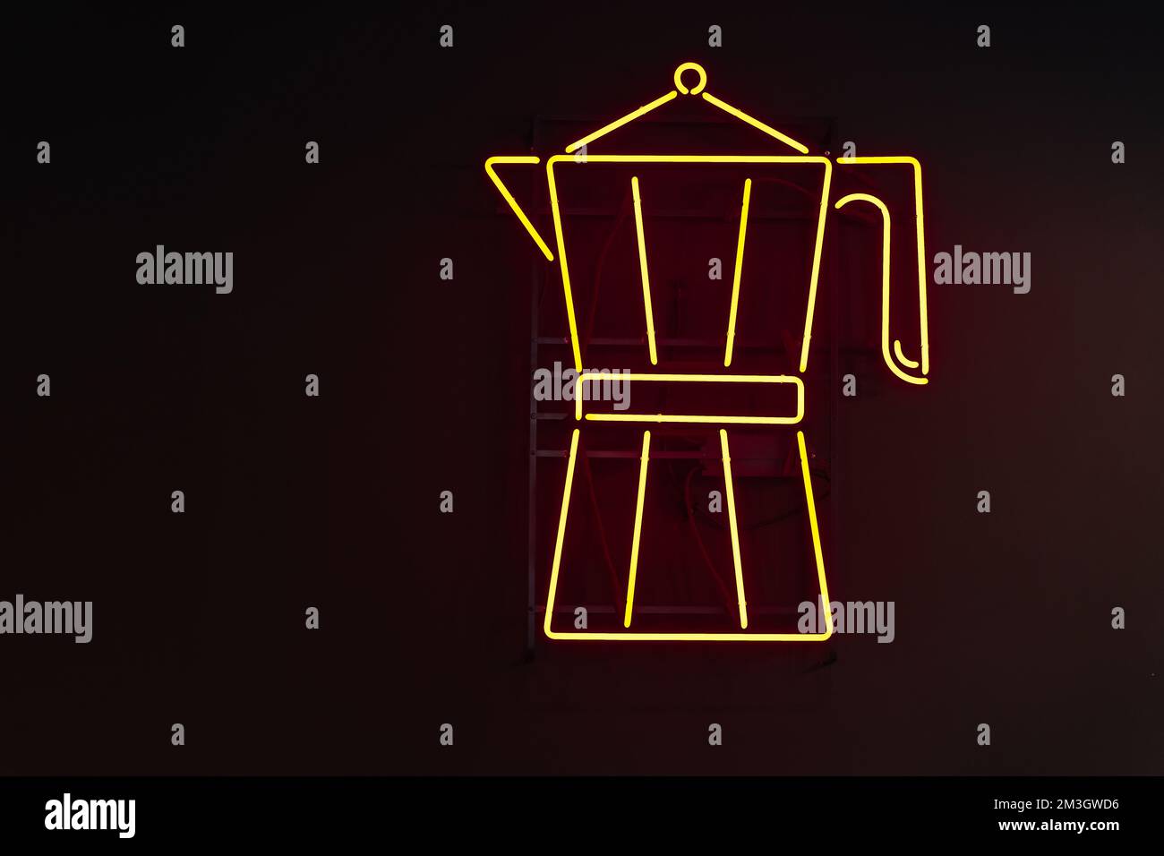Insegna gialla al neon a forma di caffettiera Moka contro una parete nera Foto Stock
