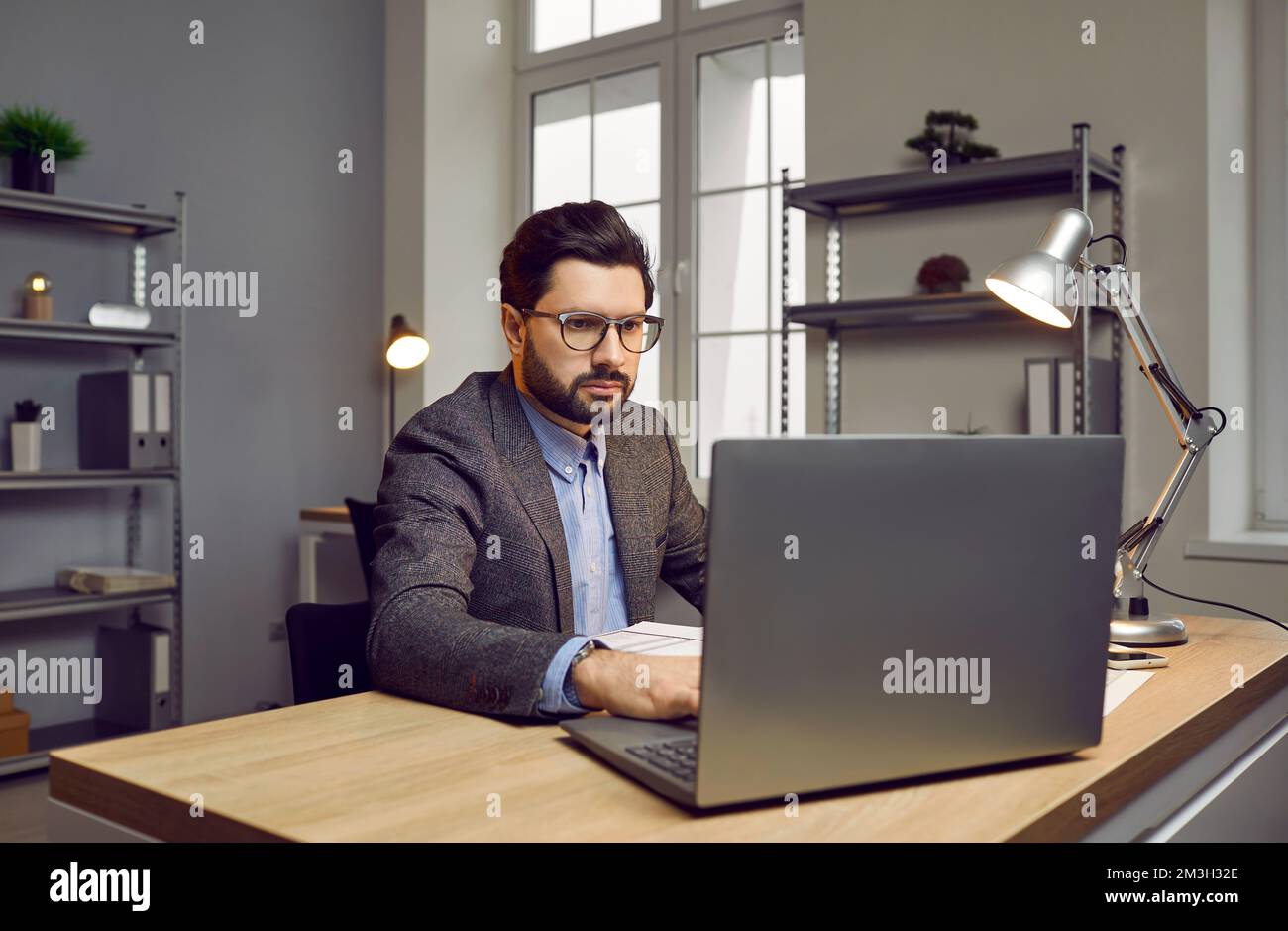 Uomo d'affari concentrato e sicuro che lavora su un notebook in un ufficio moderno Foto Stock