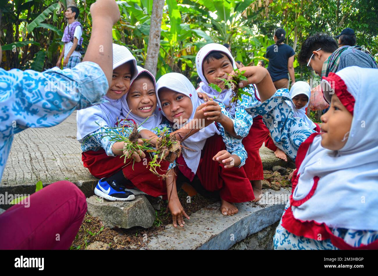 Sukamanah Village, Jambe District, Banten, Indonesia - 12 aprile 2018: Happy Energetic School Kids Playing with Plants in Front of their School SDN Suk Foto Stock