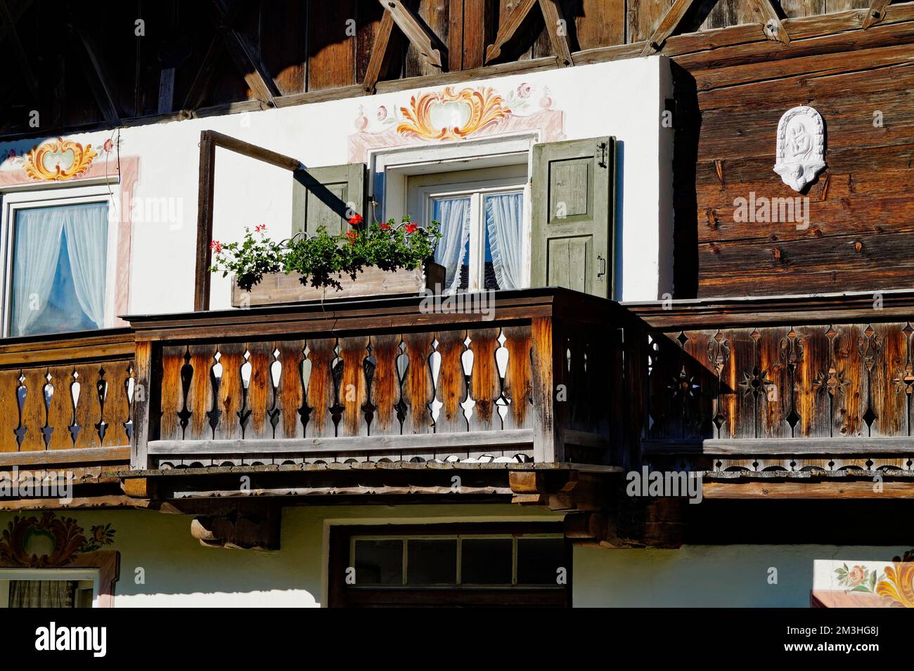 Una tradizionale casa alpina bavarese rustica con gerani sulla sporgenza del balcone e un bel balcone in legno intagliato nelle Alpi bavaresi a Garmisch Foto Stock