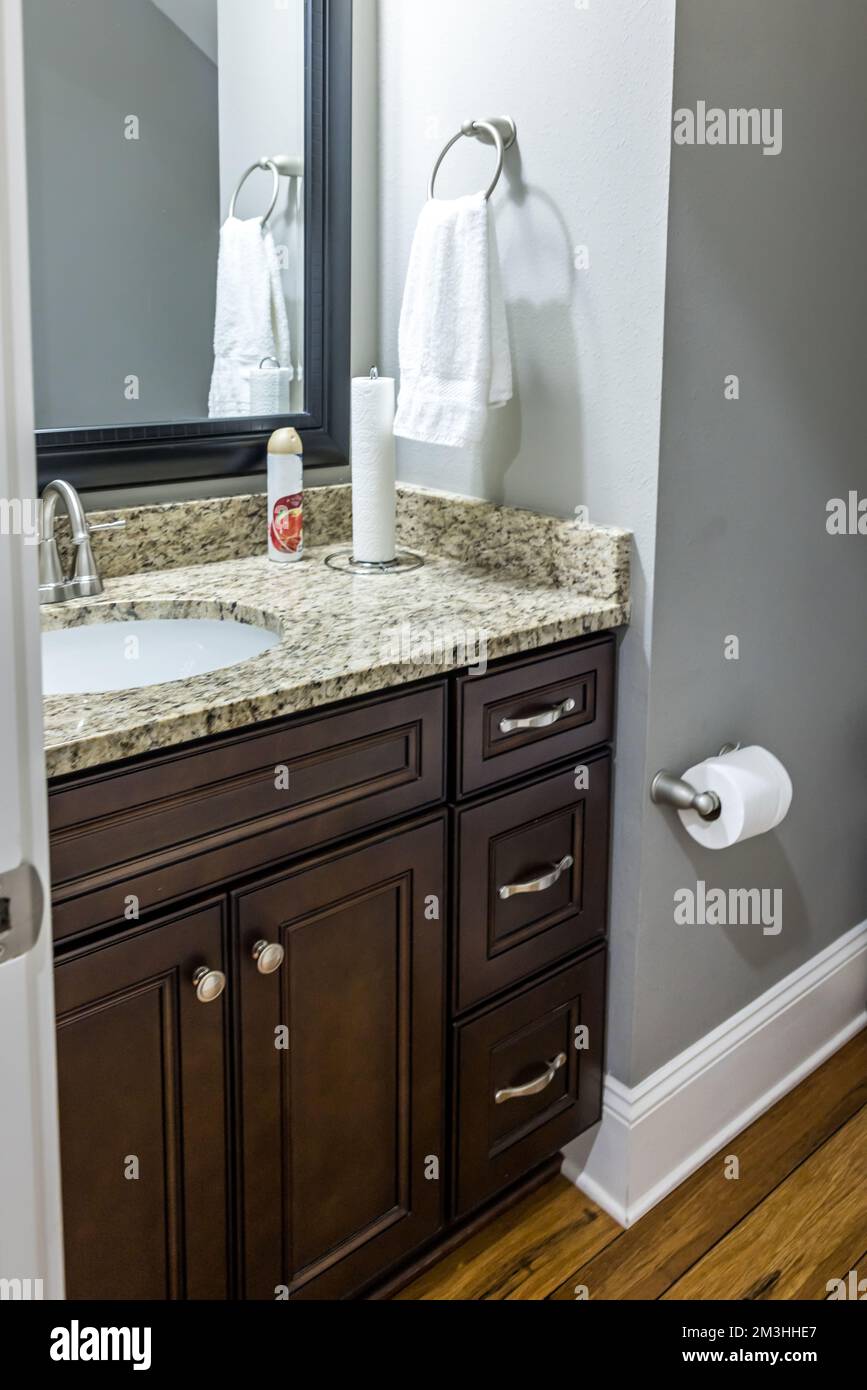 Un bagno con lavandino colorato in legno scuro con un piano di appoggio e specchio in granito Foto Stock