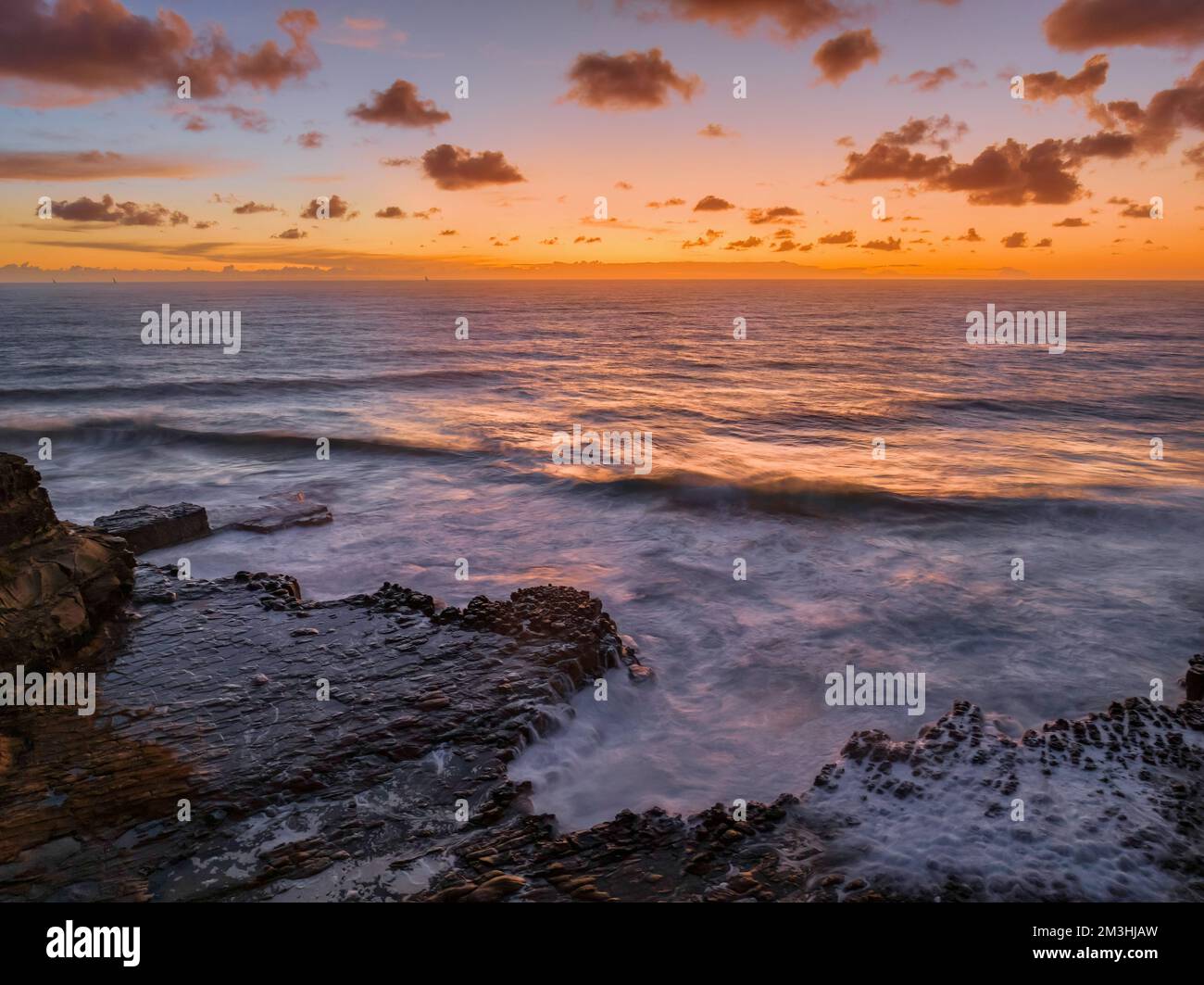 Dawn Seascape con nuvole, piattaforma rocciosa, onde di buone dimensioni e molta atmosfera a North Avoca Beach sulla costa centrale, NSW, Australia. Foto Stock