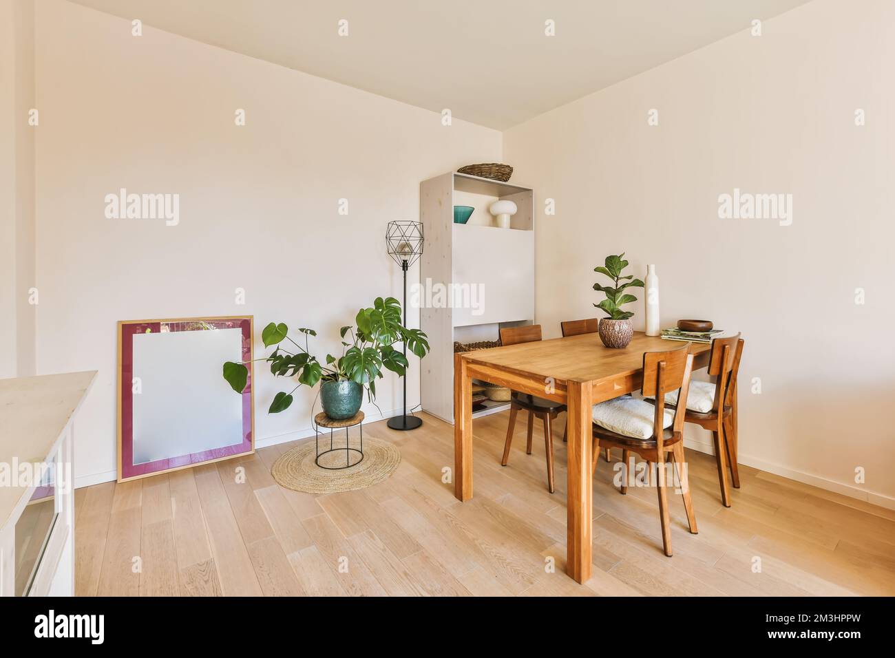 un tavolo da pranzo e sedie in una sala con pareti bianche, pavimenti in legno e parquet sul pavimento Foto Stock