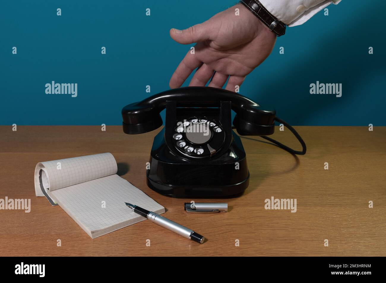installazione a posteriori. la mano raggiunge il telefono. Vecchio telefono su un tavolo di legno. spazio di copia Foto Stock