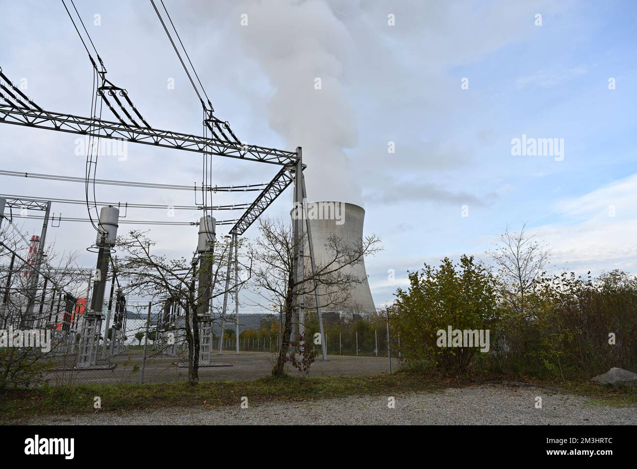 Impianto di distribuzione dell'energia elettrica ad alta tensione e torre di raffreddamento della centrale nucleare con fumo sotto il cielo blu. Foto Stock