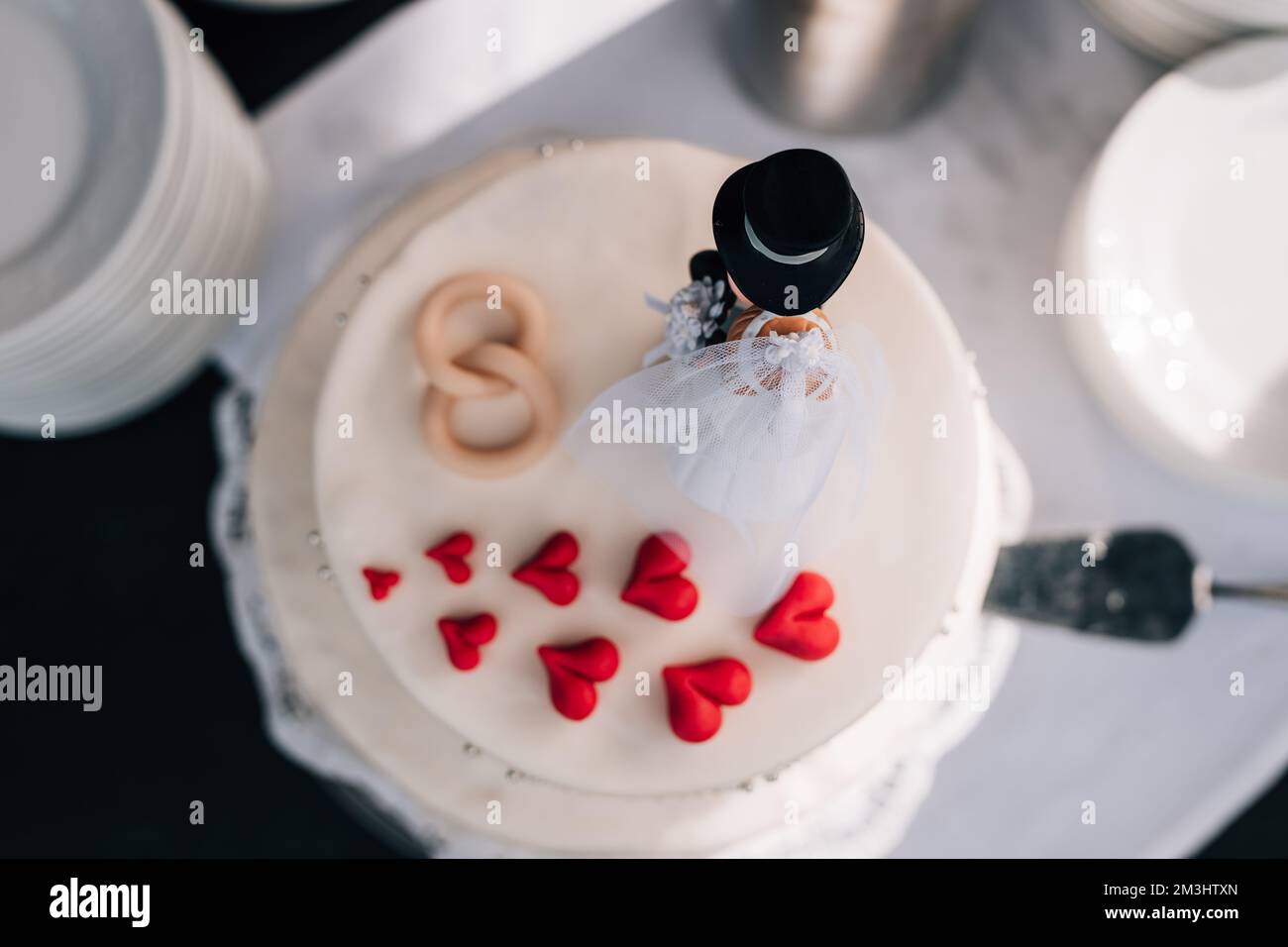 Una vista dall'alto di una torta nuziale decorata con miniatura sposa e cuori rossi Foto Stock